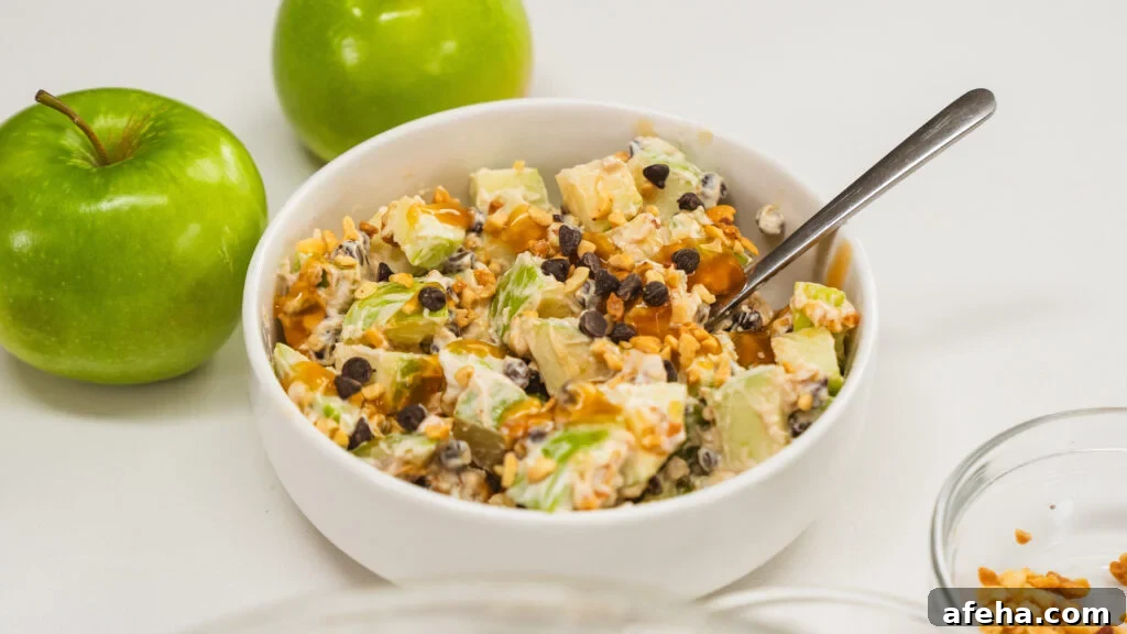 Snicker salad with apples, yogurt, chocolate chips and peanut butter. Green apples are visible to the side.