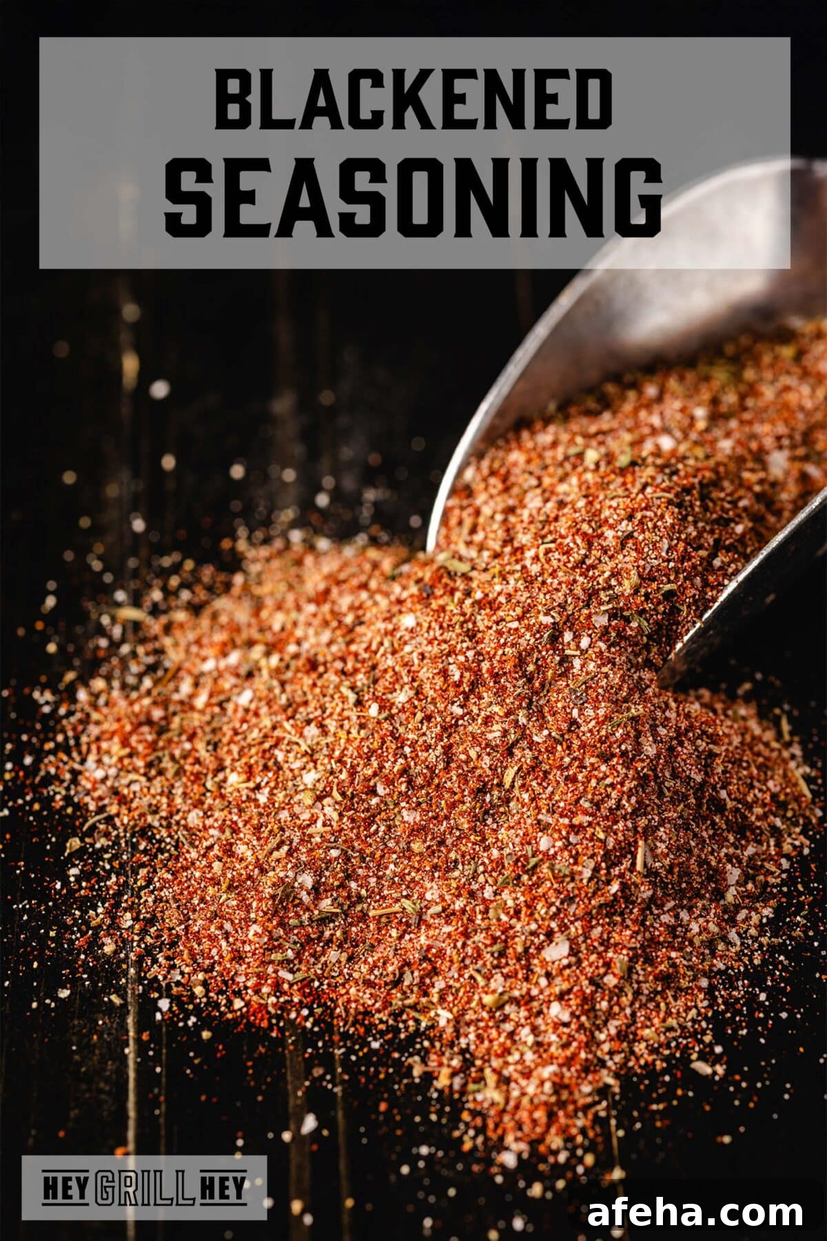 A metal scoop resting in a pile of seasoning on a black countertop. The text overlay reads 'Blackened Seasoning' at the top, and 'Hey Grill Hey' at the bottom.