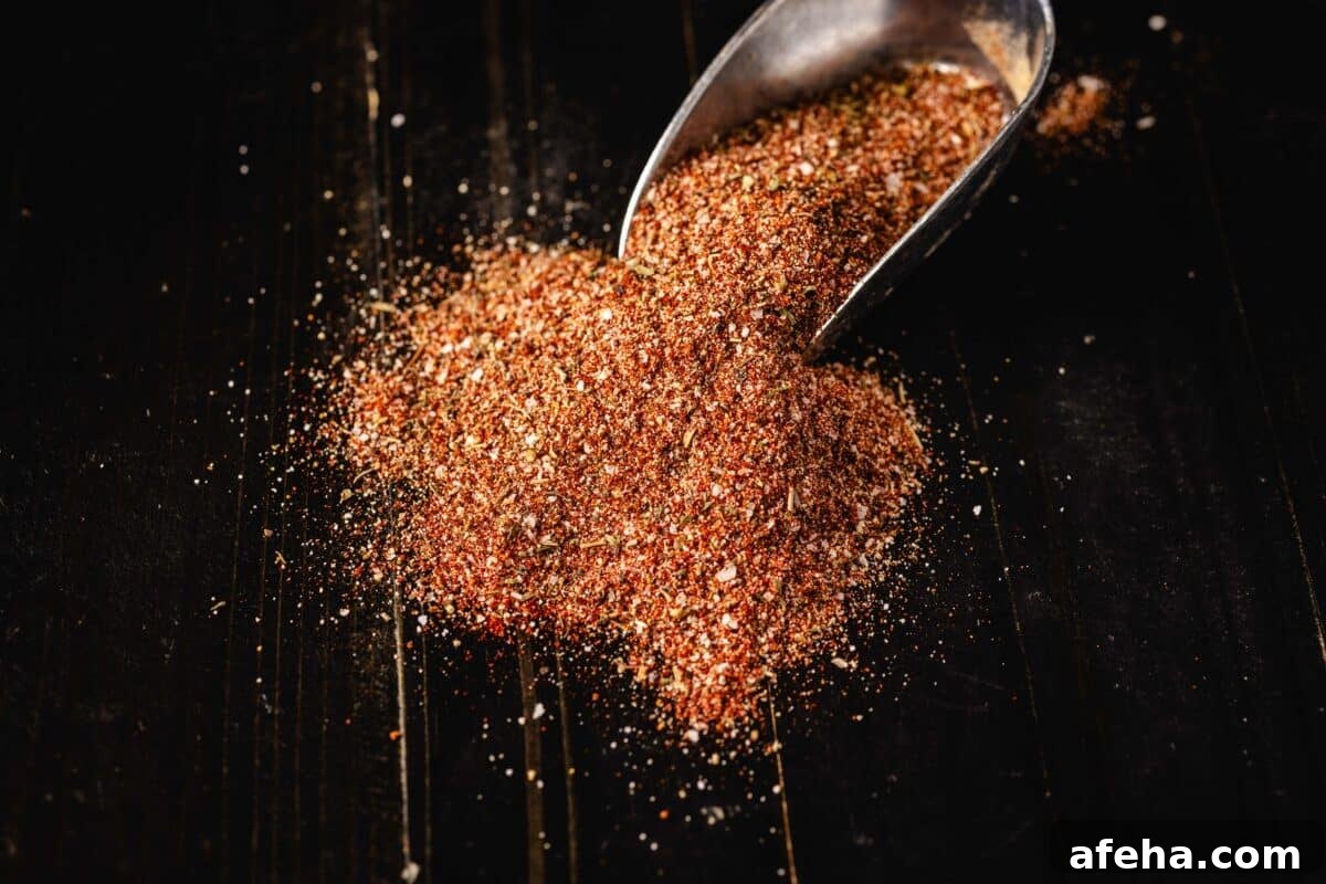 A metal scoop full of seasoning spilling out onto a table.