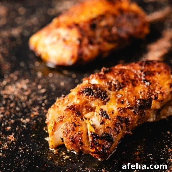 Two cooked fish fillets on a black surface.