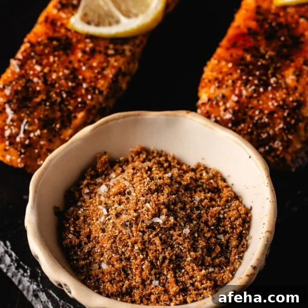 Salmon seasoning in white bowl next to grilled fillets.