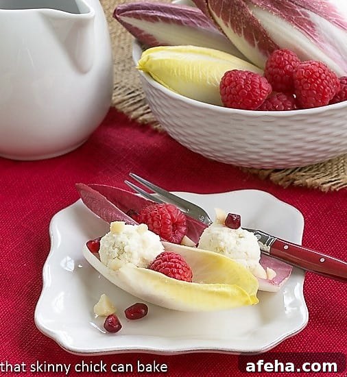 Endive Cups with Blue Cheese, Raspberries and Macadamia Nuts on a white plate.