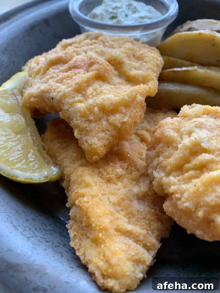 Three pieces of fried cod on a metal plate.