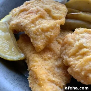 Three pieces of fried cod on a metal plate.