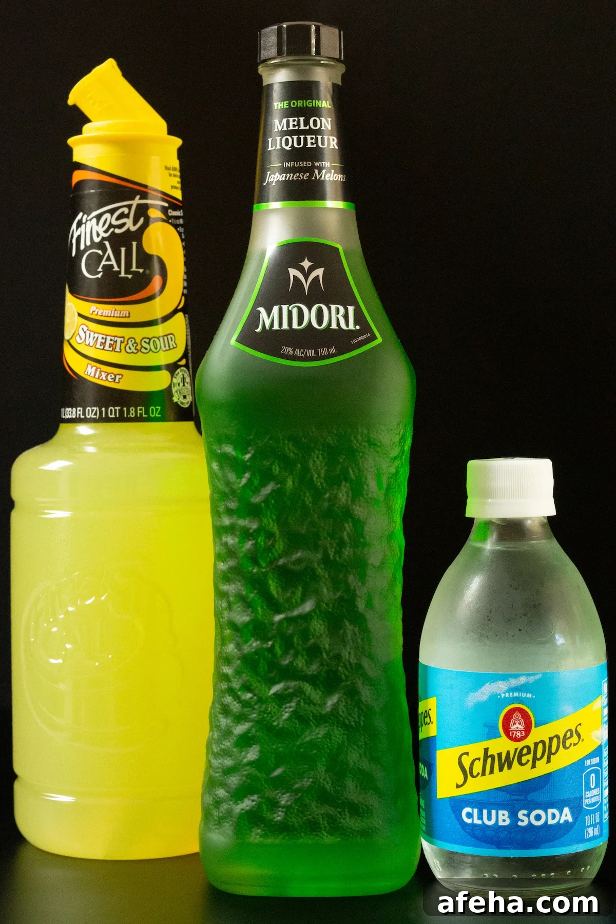 A bottle of sweet 7 sour mix, Midori, and club soda all on a black background.
