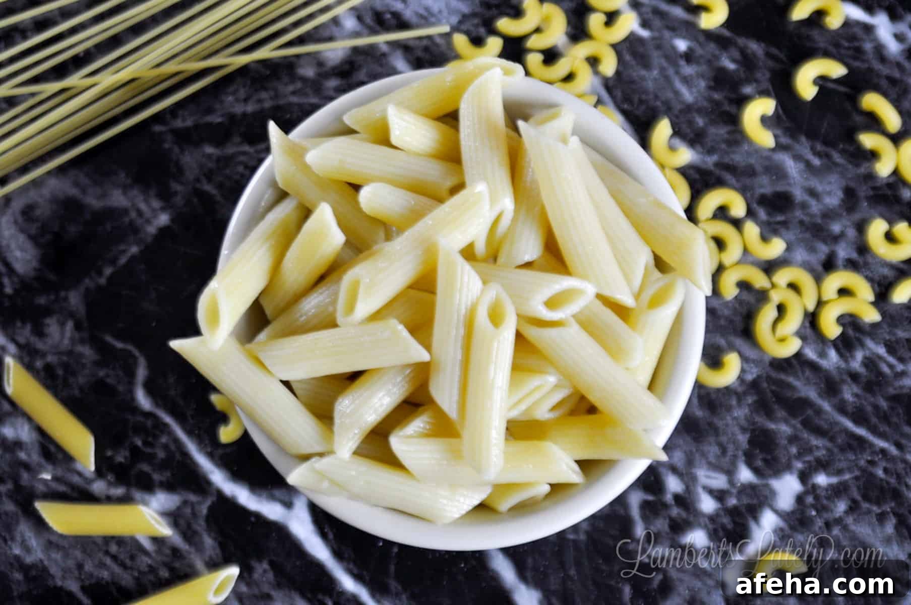 bowl of penne pasta on a black countertop.