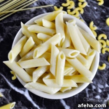 bowl of penne pasta on a black countertop.