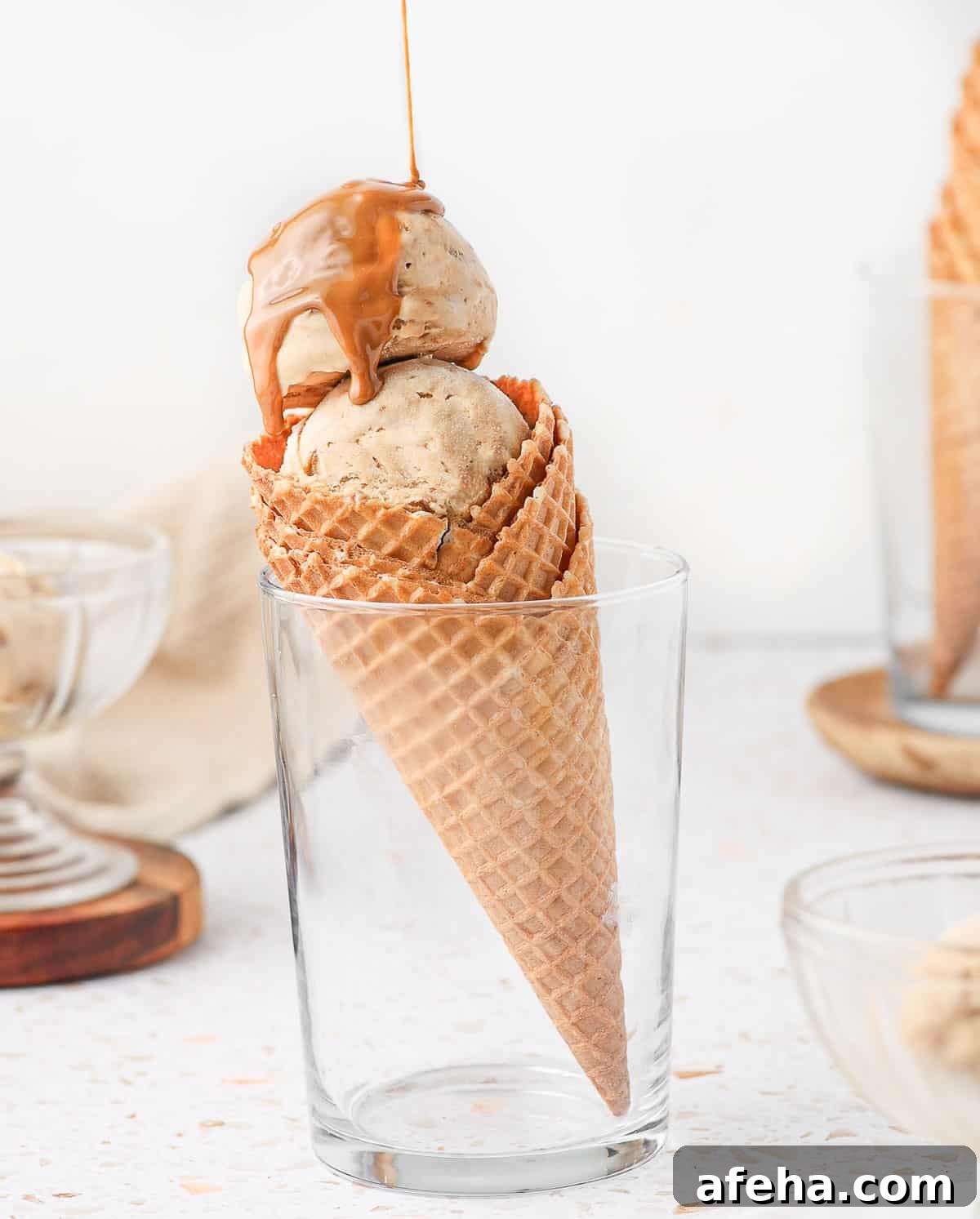 Pouring biscoff spread over the ice cream sitting in a cone.