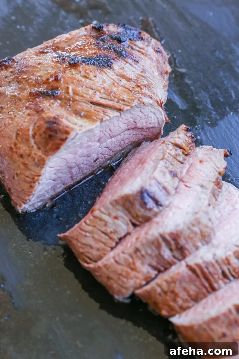 cutting board with slices of roast tri tip in its juices, ready to serve.