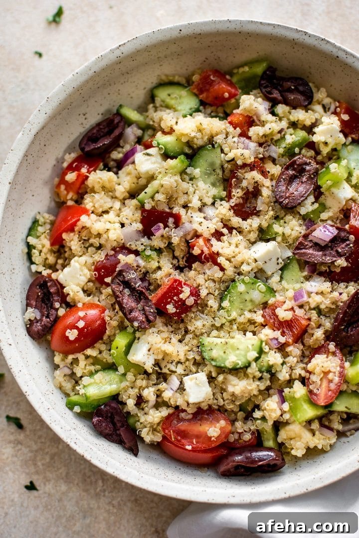 Mediterranean quinoa salad with tomatoes, feta, and olives in a beige bowl