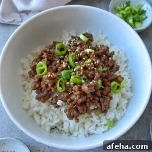Mongolian Beef with Ground Beef: Quick Savory Stir-Fry Recipe 9 A bowl of white rice topped with savory Mongolian Ground Beef, sliced green onions, and sesame seeds.