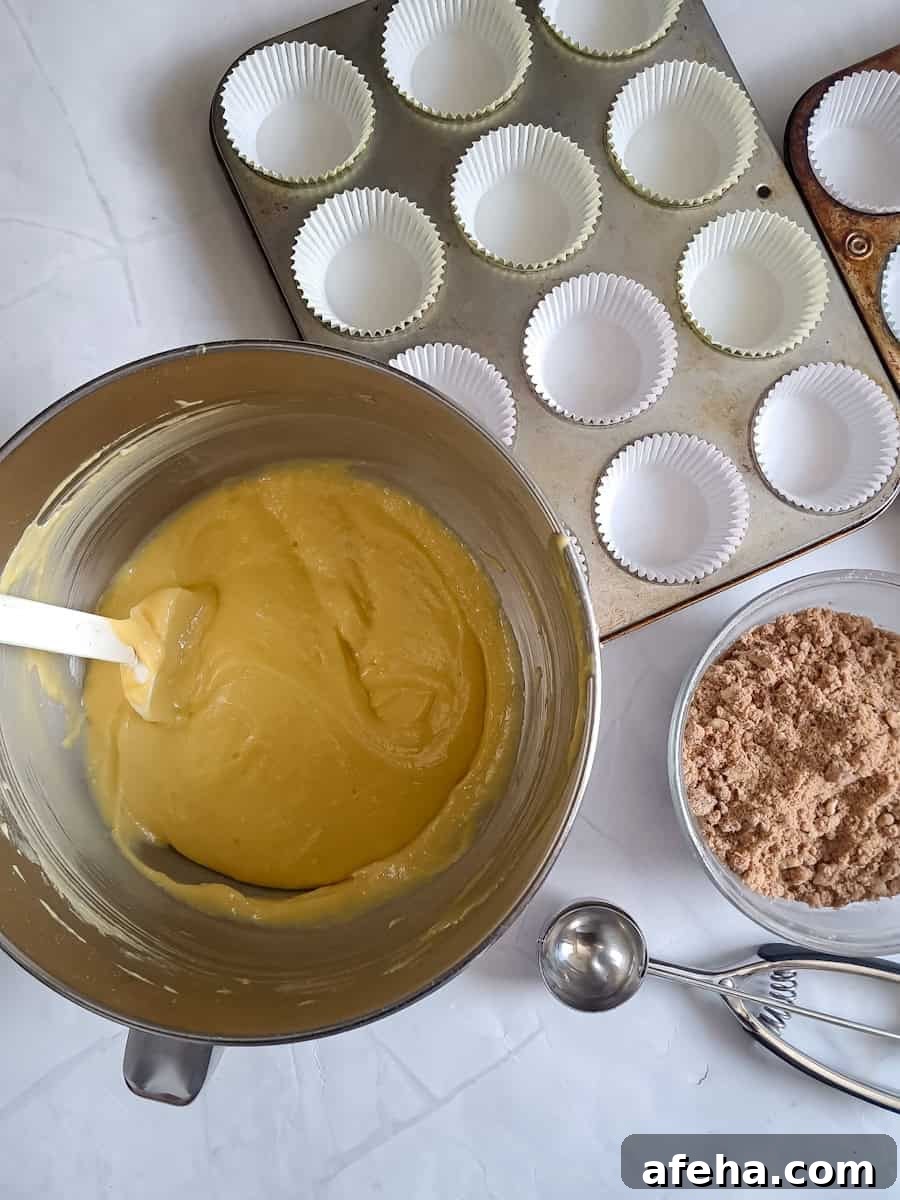 cake batter in a bowl, muffin tins ready to be filled, and streusel crumbs in another bowl.