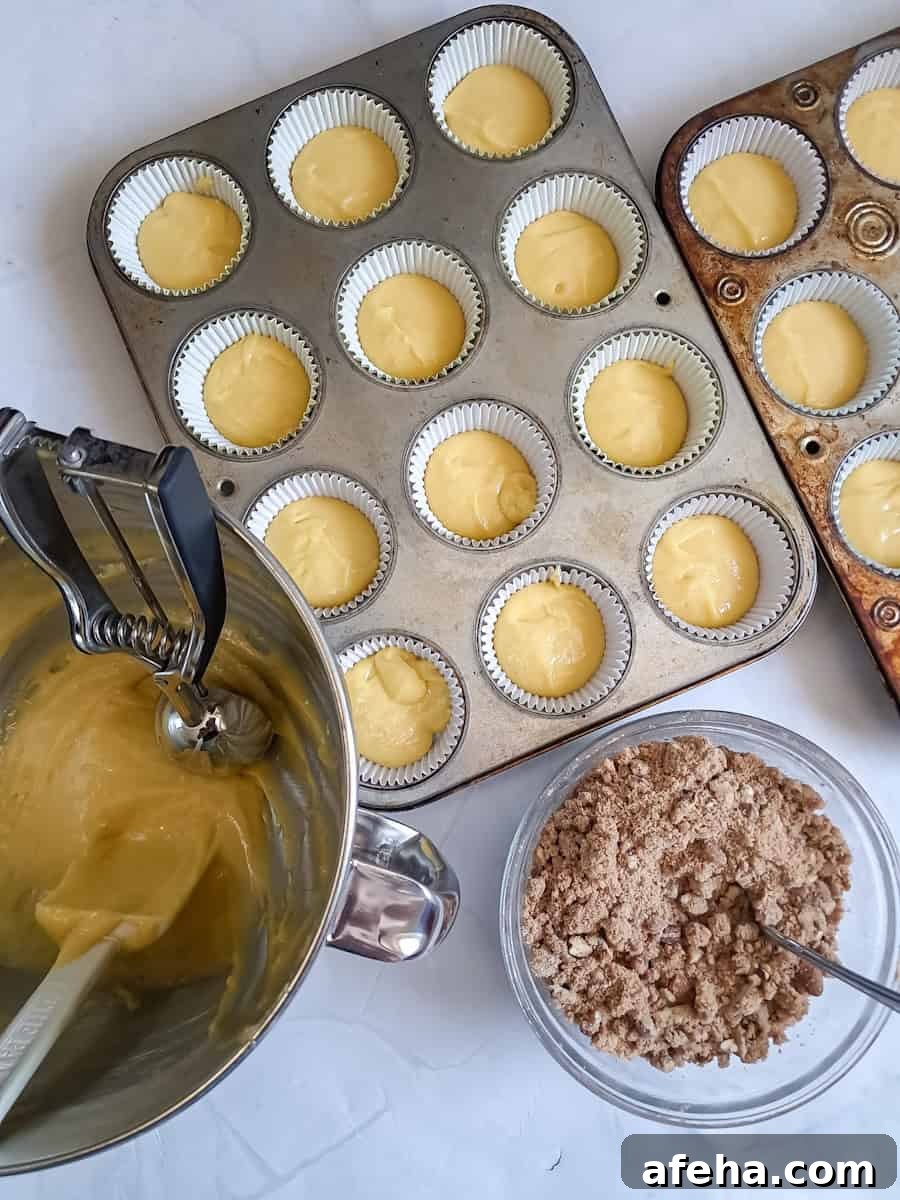 muffin tins with some batter in and now we are ready to sprinkle cinnamon crumbs over the top.