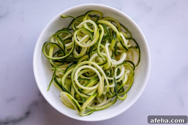 zoodles in a white bowl on a countertop shot from overhead.