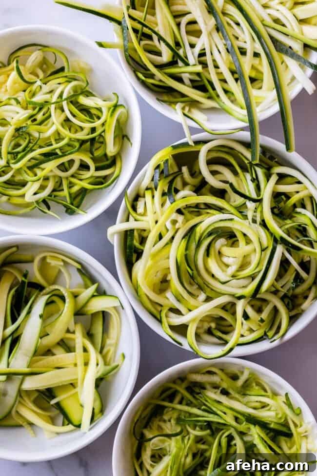 several white bowls full of zoodles made using different methods.
