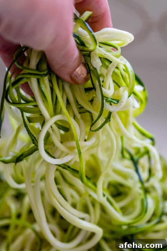 hand lifting zoodles off of counter top.