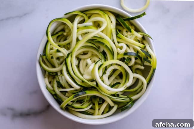 curly zoodles in a white bowl on a counter.