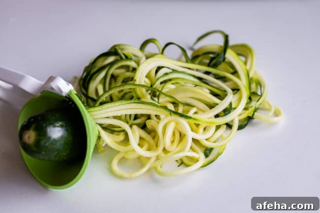 a zucchini being turned into zoodles using a handheld device.