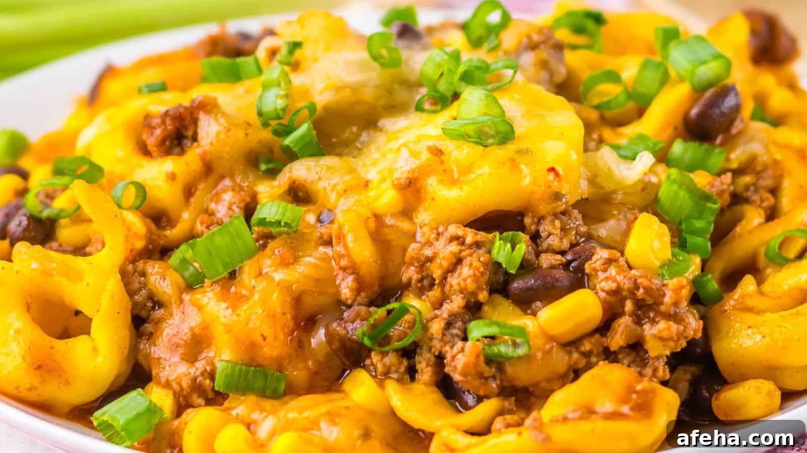 Close-up of a Beef Enchilada Tortellini dish topped with ground meat, corn, black beans, and chopped green onions.