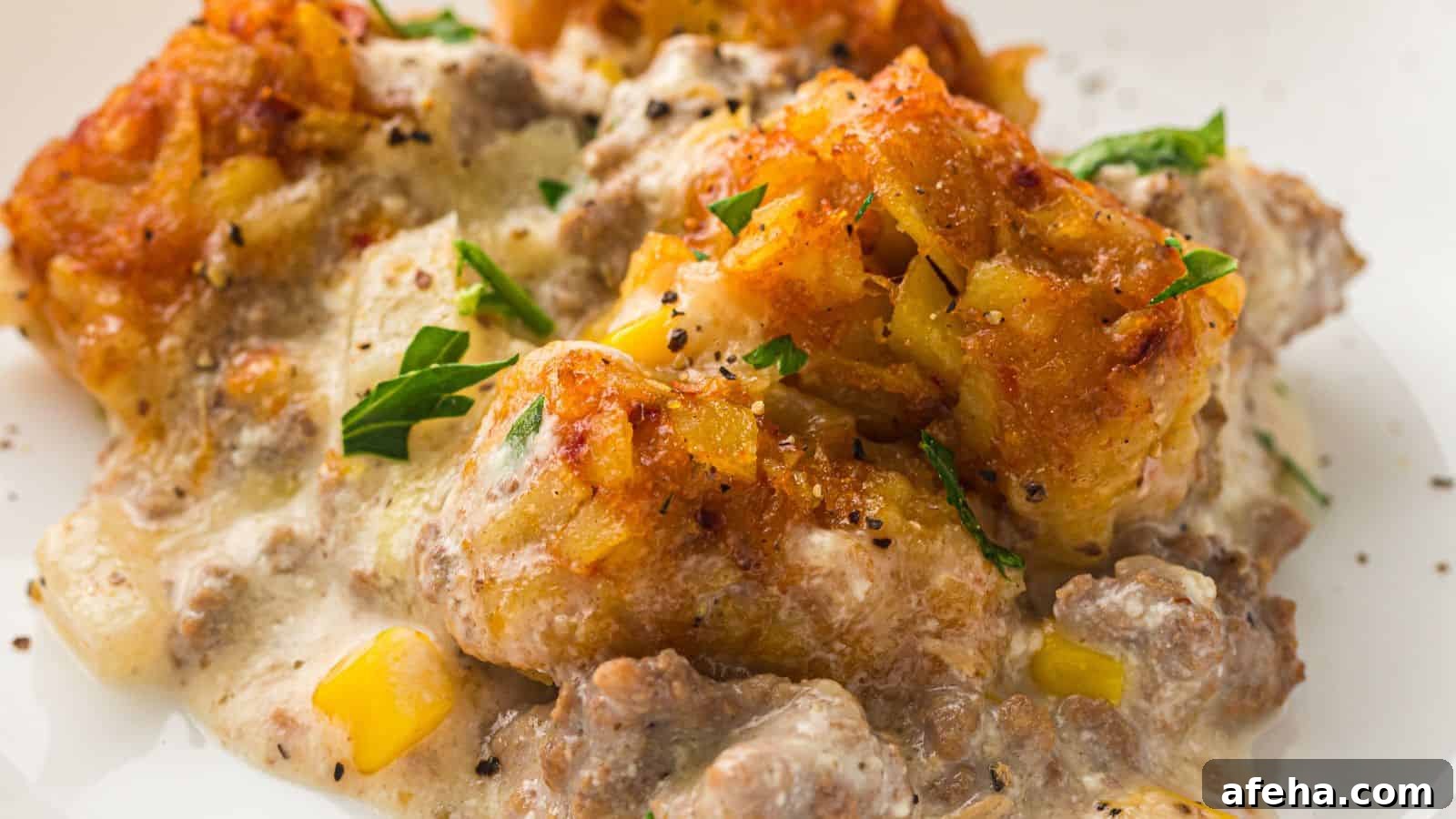 A close-up of a casserole dish featuring tater tots, creamy sauce, ground beef, corn, and garnished with chopped parsley.