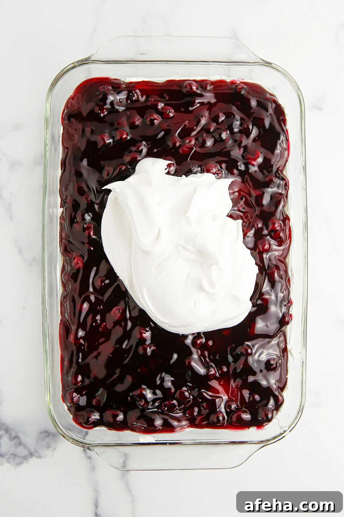 Whipped topping added over the blueberry layer in glass dish.