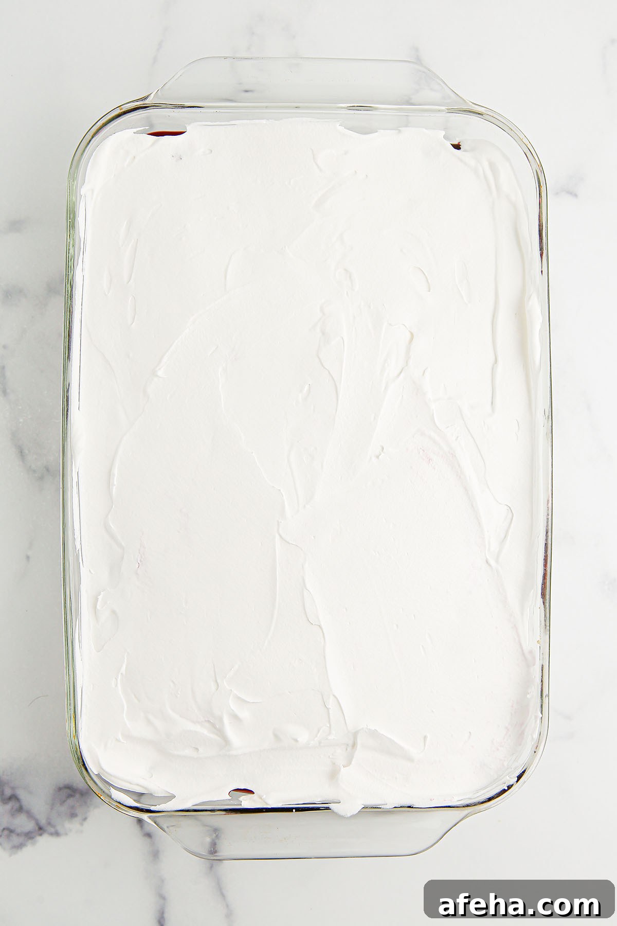 Whipped topping spread over the blueberry layer in glass dish.