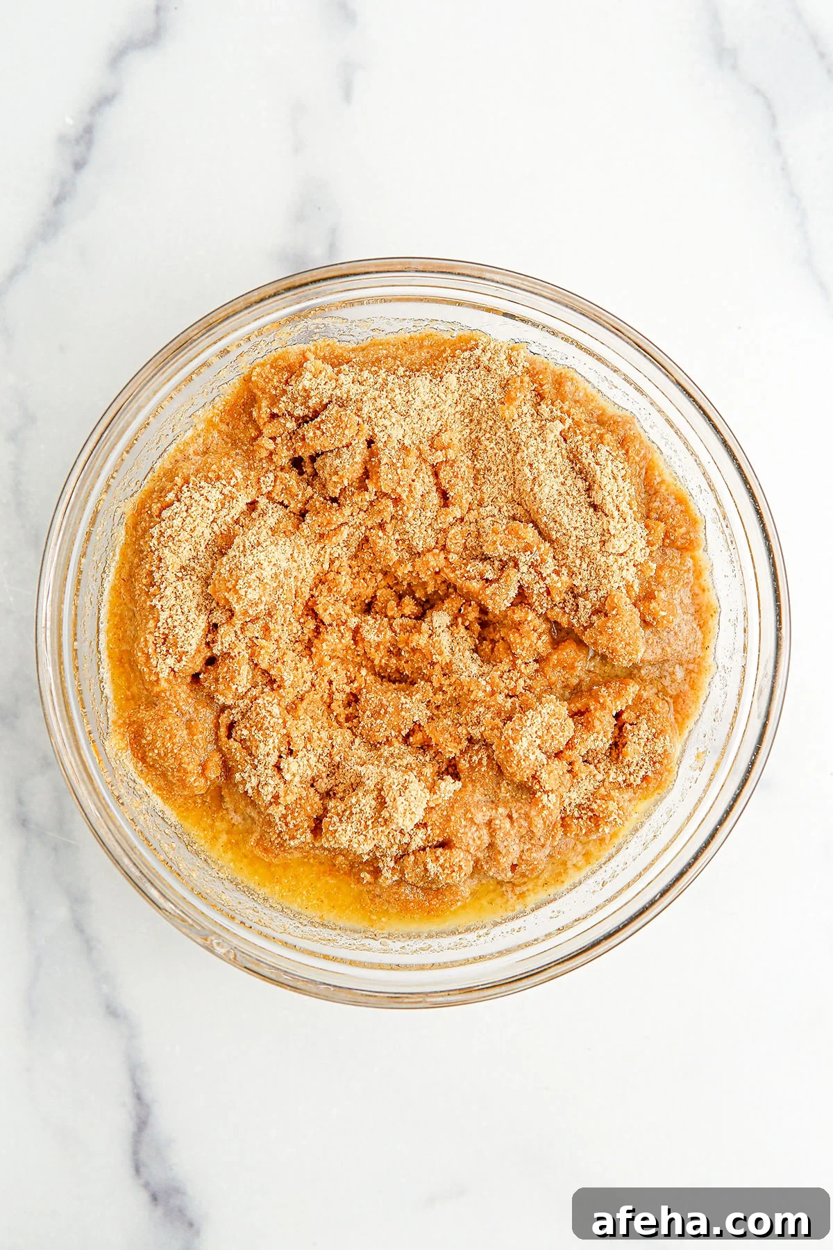 Crushed graham crackers and melted butter in a glass mixing bowl.