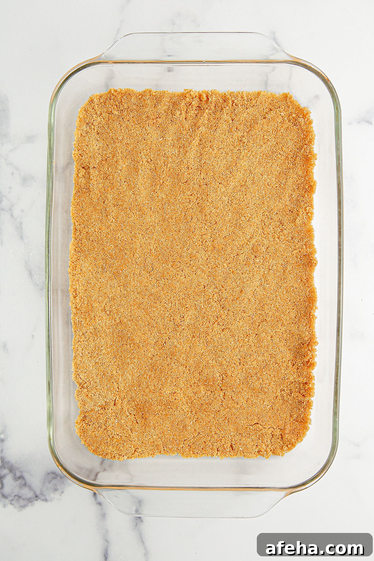 Graham cracker crust on the bottom of a glass baking dish.