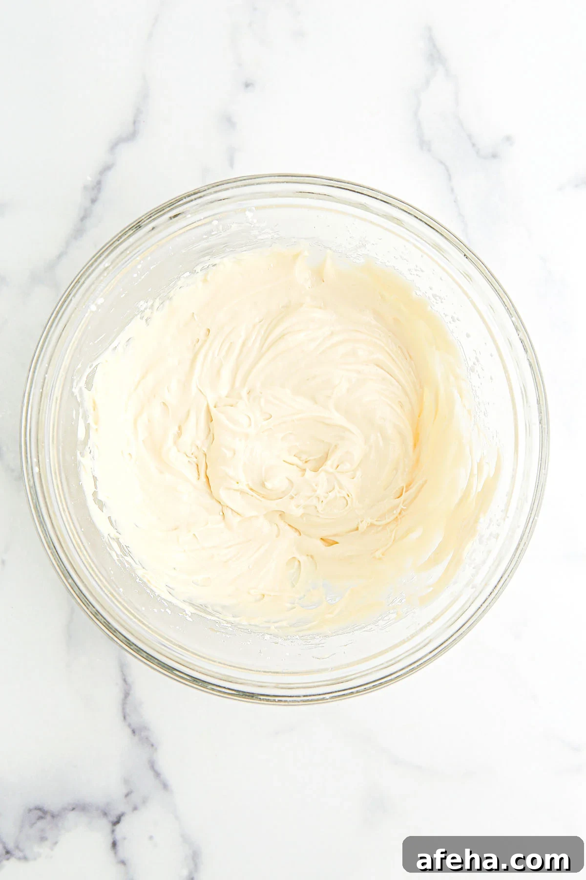 Cream cheese and powdered sugar in a glass mixing bowl.