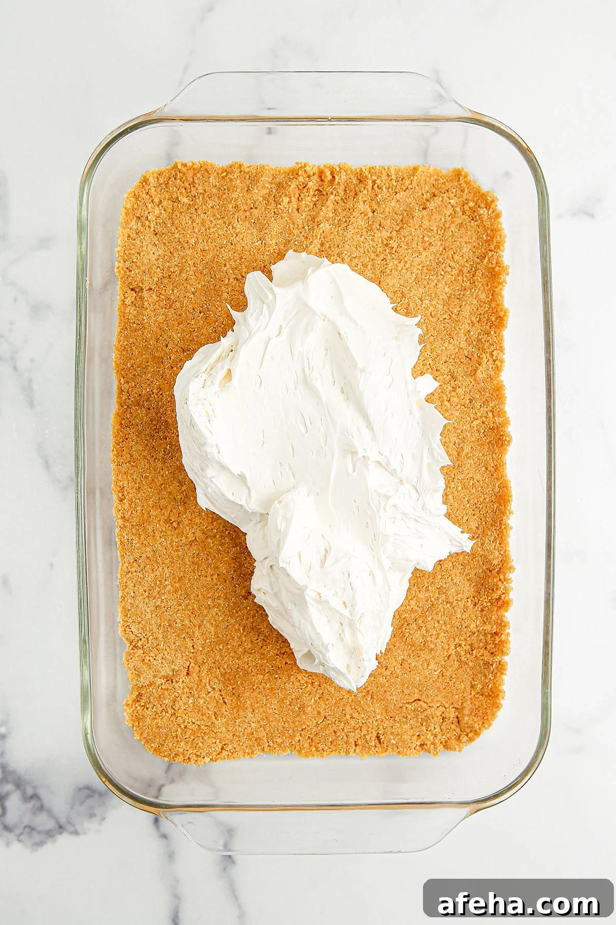 Cream cheese mixture spread over graham cracker crust in the glass baking dish.
