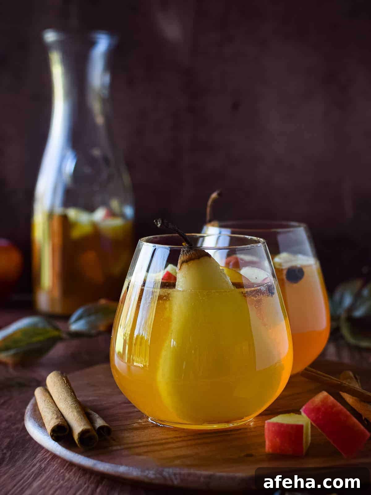 Spiced Apple & Pear White Sangria Recipe for Fall Gatherings 3 Apple and pear sangria in a glass on a wooden board.