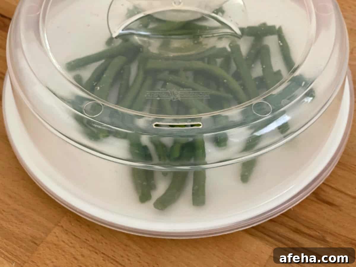Crispy Roasted Green Beans (Air Fryer or Oven) 3 Green beans on plate covered with microwave lid cover.