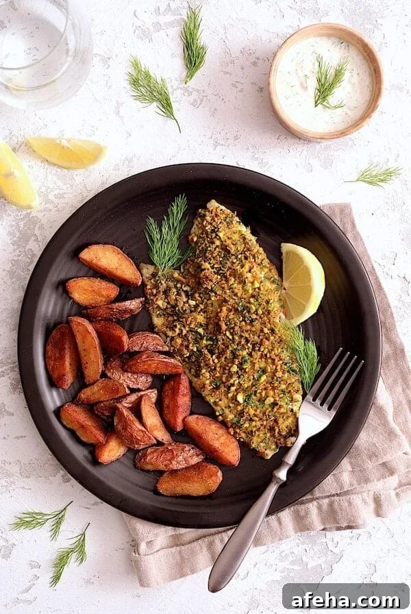 One serving of Pistachio-Crusted Fish with Lemon-Dill Aioli with roasted potatoes on black dinner plate.