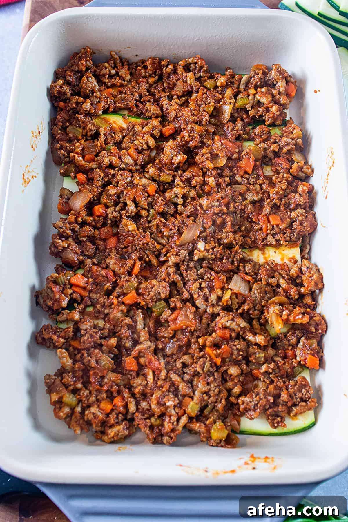 a 9x13 dish with layers of sliced zucchini and layered ground meat.