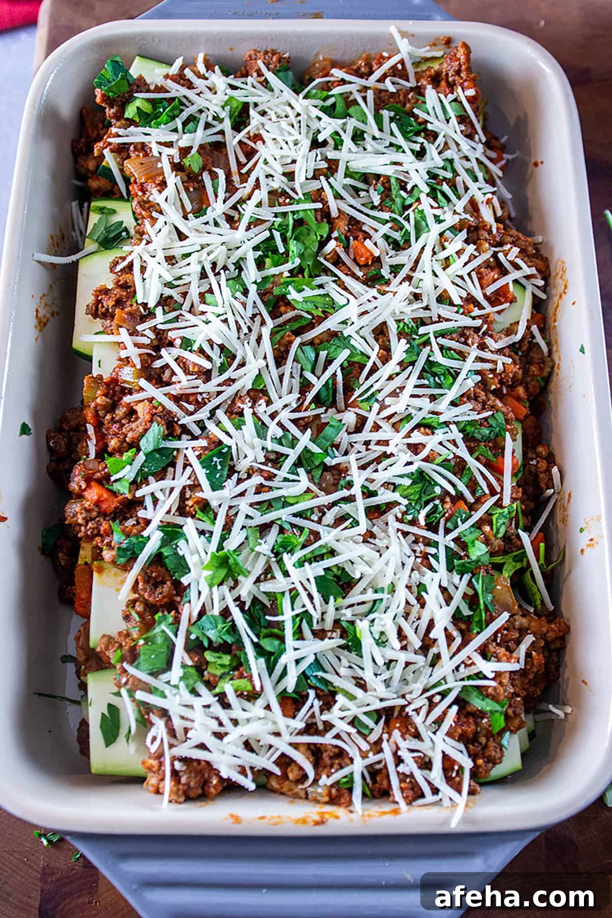 Pan filled with a zucchini lasagna topped with parmesan cheese and fresh parsley.