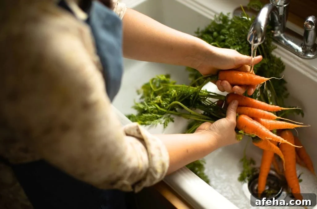 Washing fresh carrots at a white kitchen sink.