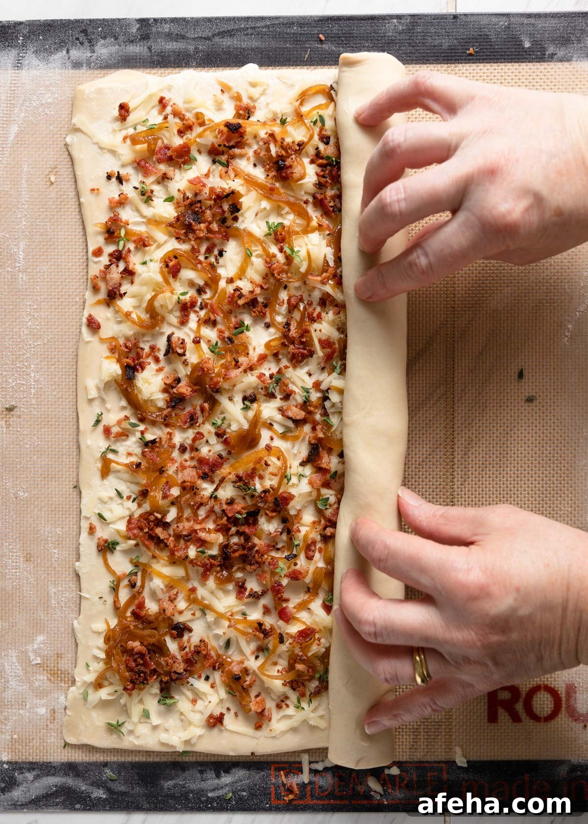 rolling bacon, caramelized onion, and gruyere puff pastry into palmiers