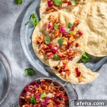 Indian onion chutney spread over poppadoms on a grey background.