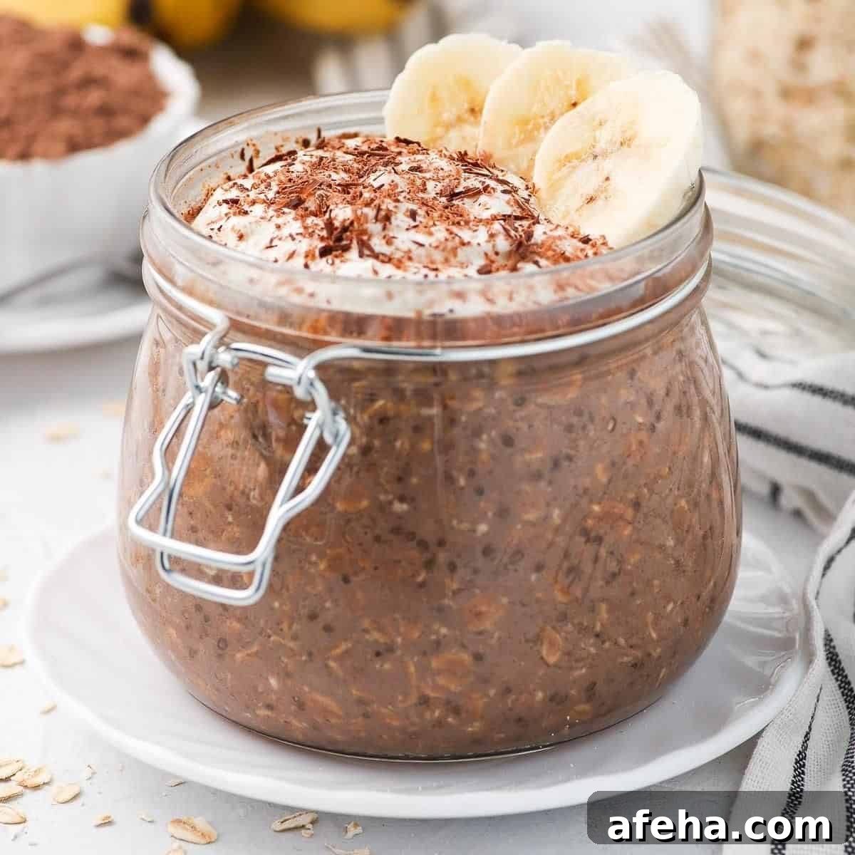 Jar of oats, topped with yoghurt, slices of banana and shaved chocolate.