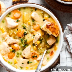 Creamy Chicken Pot Pie Soup Recipe for Cozy Weeknight Meals 2 Overhead view of a bowl of chicken pot pie soup garnished with thyme, next to some biscuits.