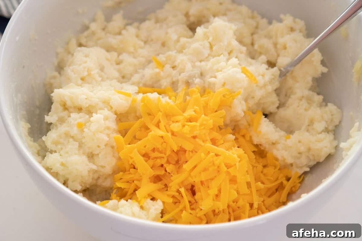 cheddar cheese and mashed potatoes in large white bowl