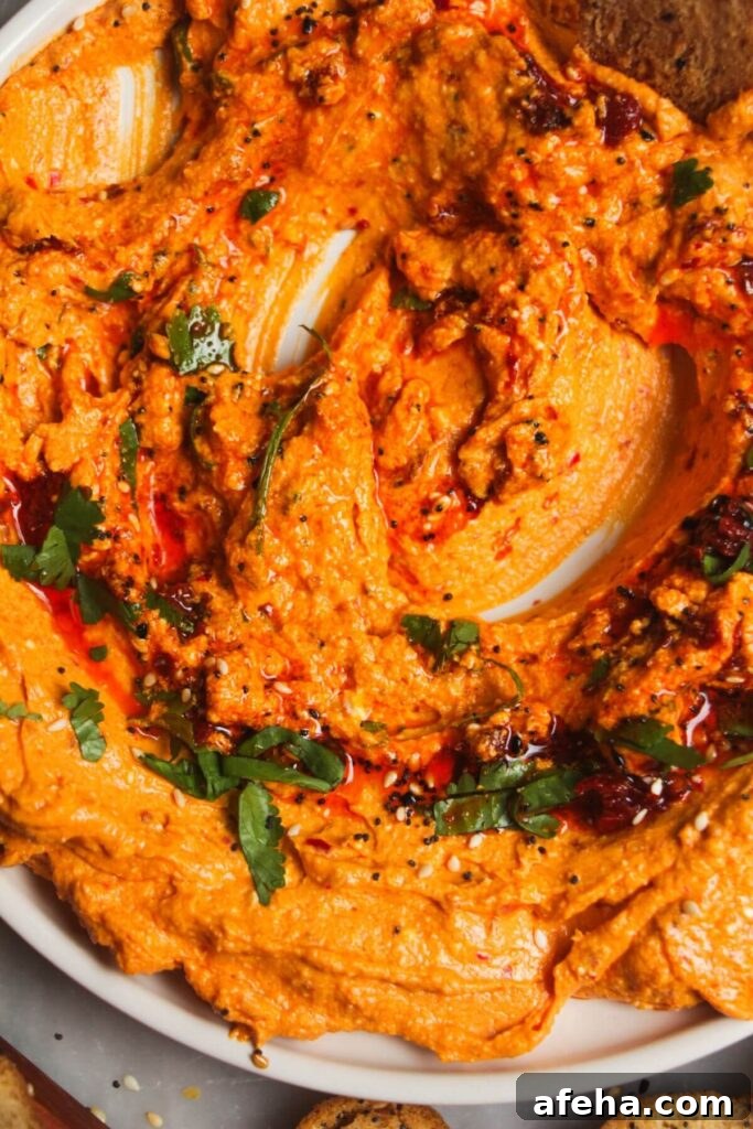 Close up of spicy feta harissa dip on a small white plate with harissa and parsley on top.