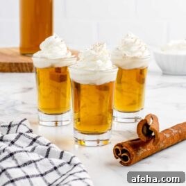 a close up shot of Cinnamon Roll Fireball Shot in cups topped with whipped cream