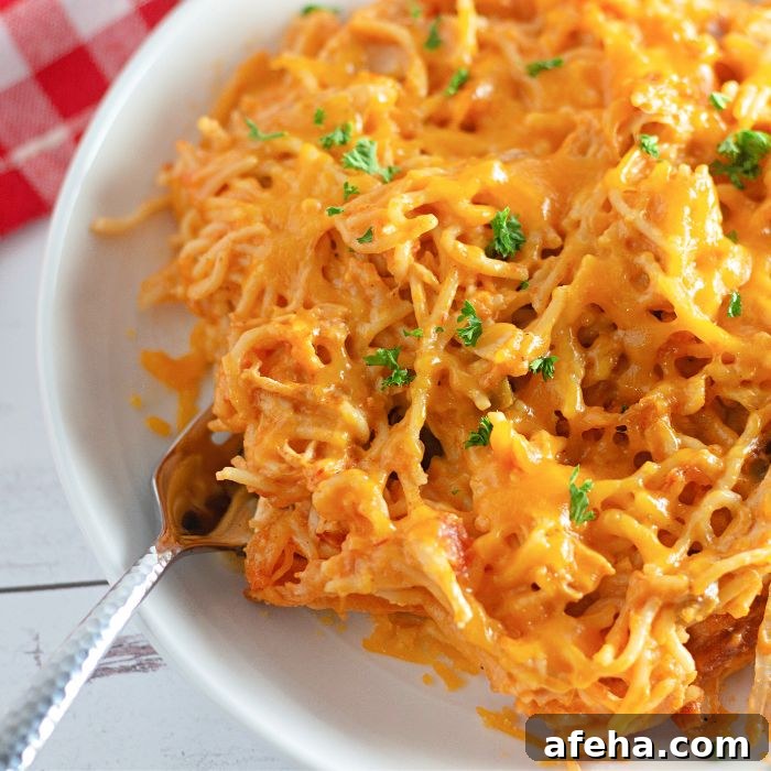 white plate with chicken spaghetti on it with a fork on it