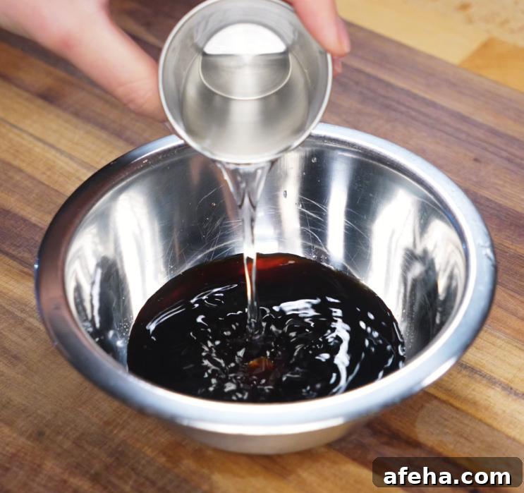 Sake is poured into a bowl of soy sauce and mirin, forming the savory-sweet marinade that gives ginger pork its signature flavor.