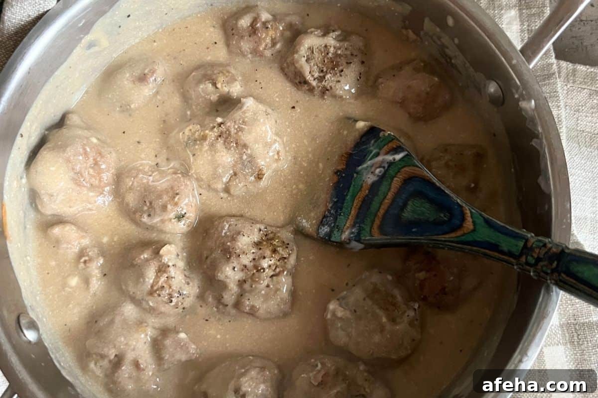 Swedish-Style Turkey Meatballs with Creamy Dill Sauce 7 Swedish meatballs added to gravy mixture in a pot.