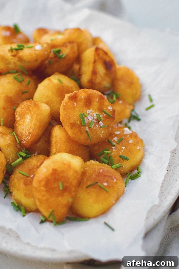Crispy Roasted Potatoes on a platter topped with flakey sea salt and chopped chives.