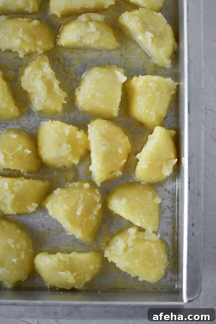 Placing the tossed & "fuzzed" potatoes into a pan that has been warmed in the oven with hot oil in it.