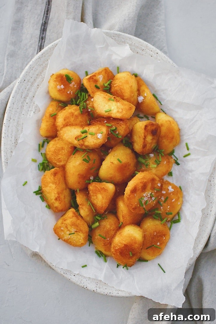 Crispy Roasted Potatoes on a platter topped with flakey sea salt and chopped chives.