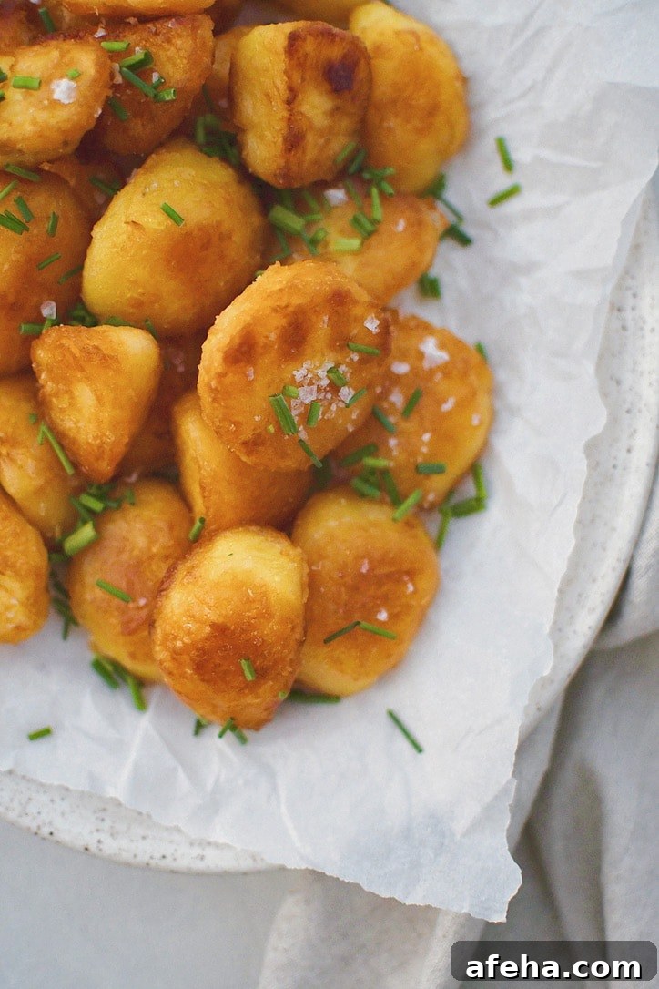 Crispy Roasted Potatoes on a platter topped with flakey sea salt and chopped chives.